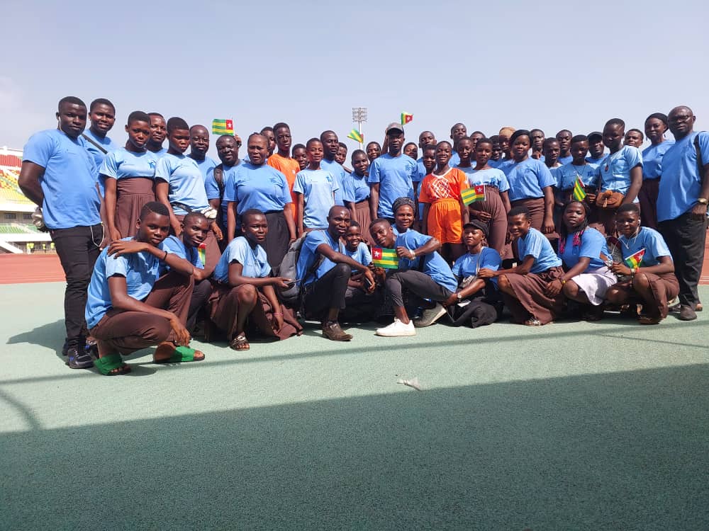 Grand groupe de jeunes du centre réunis dans un stade avec des drapeaux du Togo