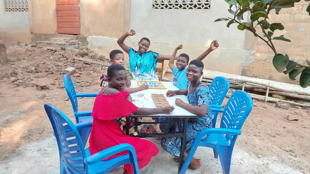 Quatre enfants jouent à un jeu de société dans la cour du centre