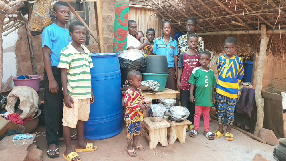 Une famille devant le matériel de cuisine et le fût d'eau reçus du centre